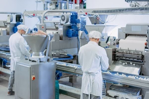 Workers on a food manufacturing production line packaging dry goods, representing Henry Broch Foods' integrated co-packing and ingredient sourcing operations