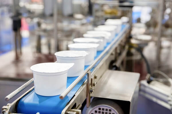 Sealed white cups moving along conveyor belt in CPG manufacturing facility